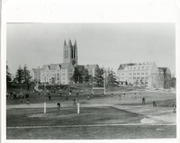 Alumni Field during football practice with view of Devlin Hall under construction and Gasson Hall