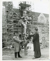 Lyons Hall exterior during construction, William L. Keleher wishes worker good luck as worker prepares to ride with cross to the roof