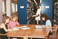 O&#39;Neill Library interior: students studying at table and browsing the stacks