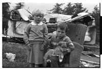 Two children in an armchair with dog, in front their caravan, allegedly burnt by local area residents, Flying Horse Road, Downpatrick