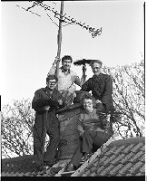 Alfie Crozier with wife and sons, chimney sweeps holding brushes on their roof beside the chimney