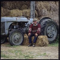 Robin Matthews on hay bale with tractor behind him