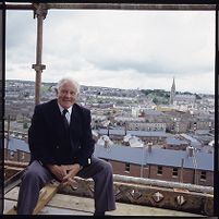 Paddy &quot;Bogside&quot; Doherty on scaffolding of new business project, with him in the background and with wall mural in the background, Derry