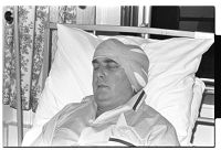 Eddie McGrady with head bandage in a hospital bed