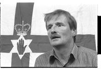 Sammy Duddy, standing in front of the Ulster flag at the Ulster Defense Association Headquarters, Belfast