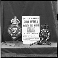 Original &quot;Dan Breen Wanted&quot; poster beside police crests from an earlier era, Royal Irish Constabulary and Irish Constabulary