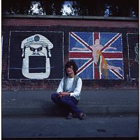 Mairead Corrigan in front of Sinn Fein republican wall mural, Falls Road